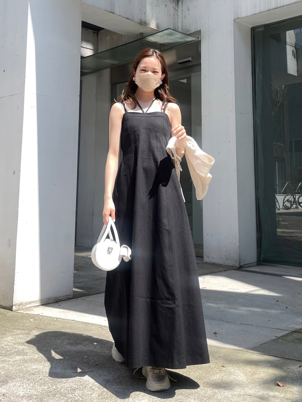 ブラック系のワンピース、ホワイト系のカーディガン/ボレロ、ホワイト系のショルダーバッグを着用したレディースの春コーディネートの3枚目の写真