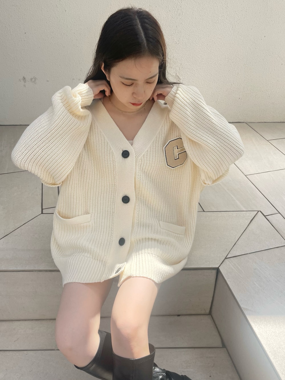 ホワイト系のカーディガン/ボレロ、ホワイト系のキャミソール、ブラック系のブーツを着用したレディースの夏コーディネートの2枚目の写真