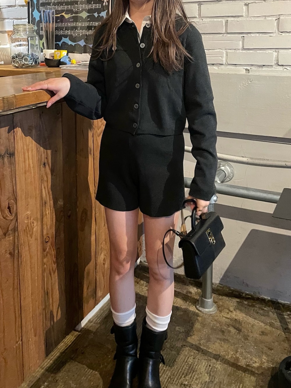 グレー系のカーディガン/ボレロ、ブラック系のショルダーバッグ、ホワイト系のベストを着用したレディースの春コーディネートの3枚目の写真