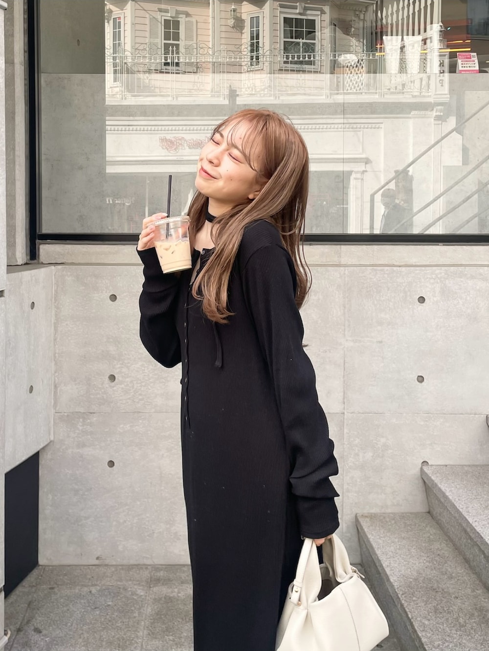 ブラック系のブーツ、ブラック系のワンピース、ホワイト系のハンドバッグを着用したレディースの春コーディネートの2枚目の写真