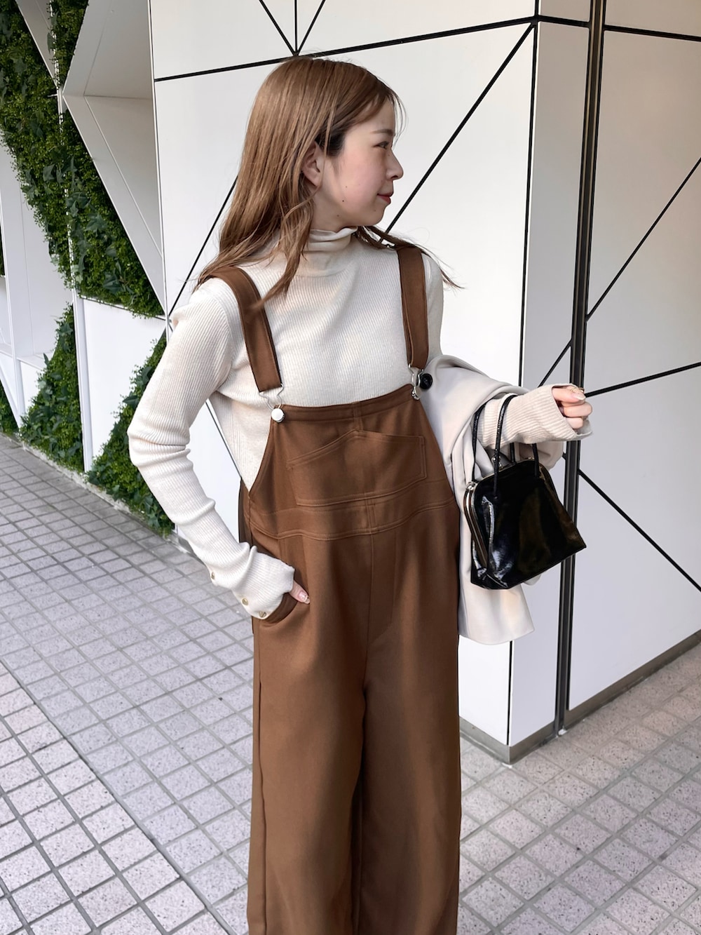 ブラウン系のサロペット/オーバーオール、ブラック系のショルダーバッグ、ホワイト系のニット/セーターを着用したレディースの冬コーディネートの2枚目の写真