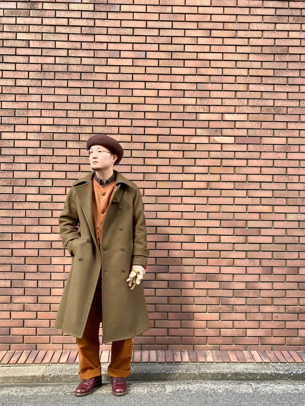 ブラウン系のその他パンツ、レッド系のドレスシューズ、グリーン系のピーコートを着用したメンズの冬コーディネートの2枚目の写真