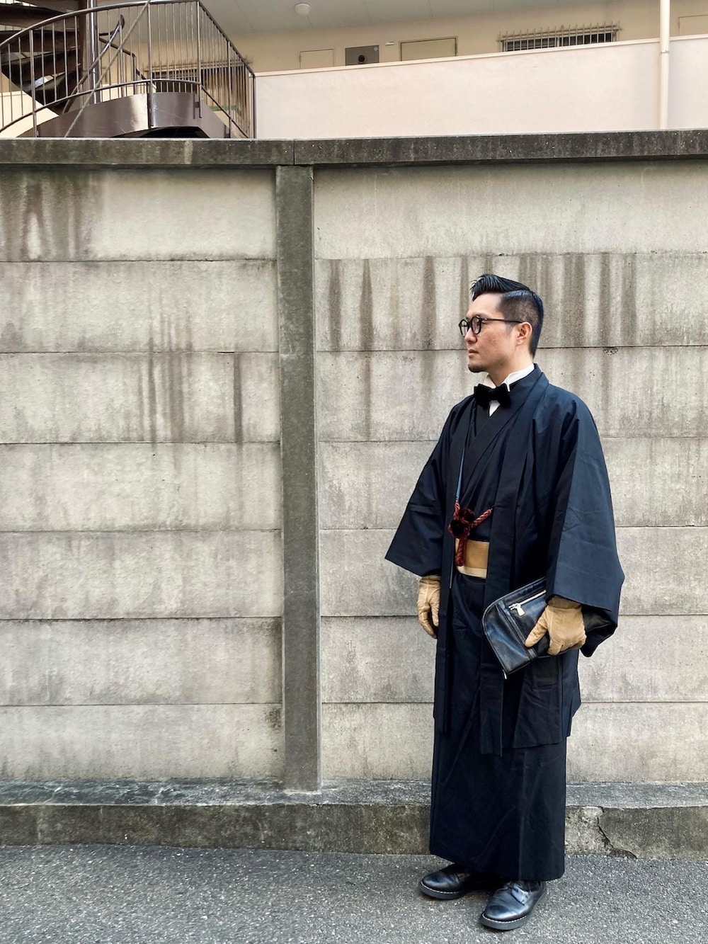 ブラック系のブーツ、ブラック系の蝶ネクタイ、ブラック系のクラッチバッグを着用したメンズの冬コーディネートの3枚目の写真