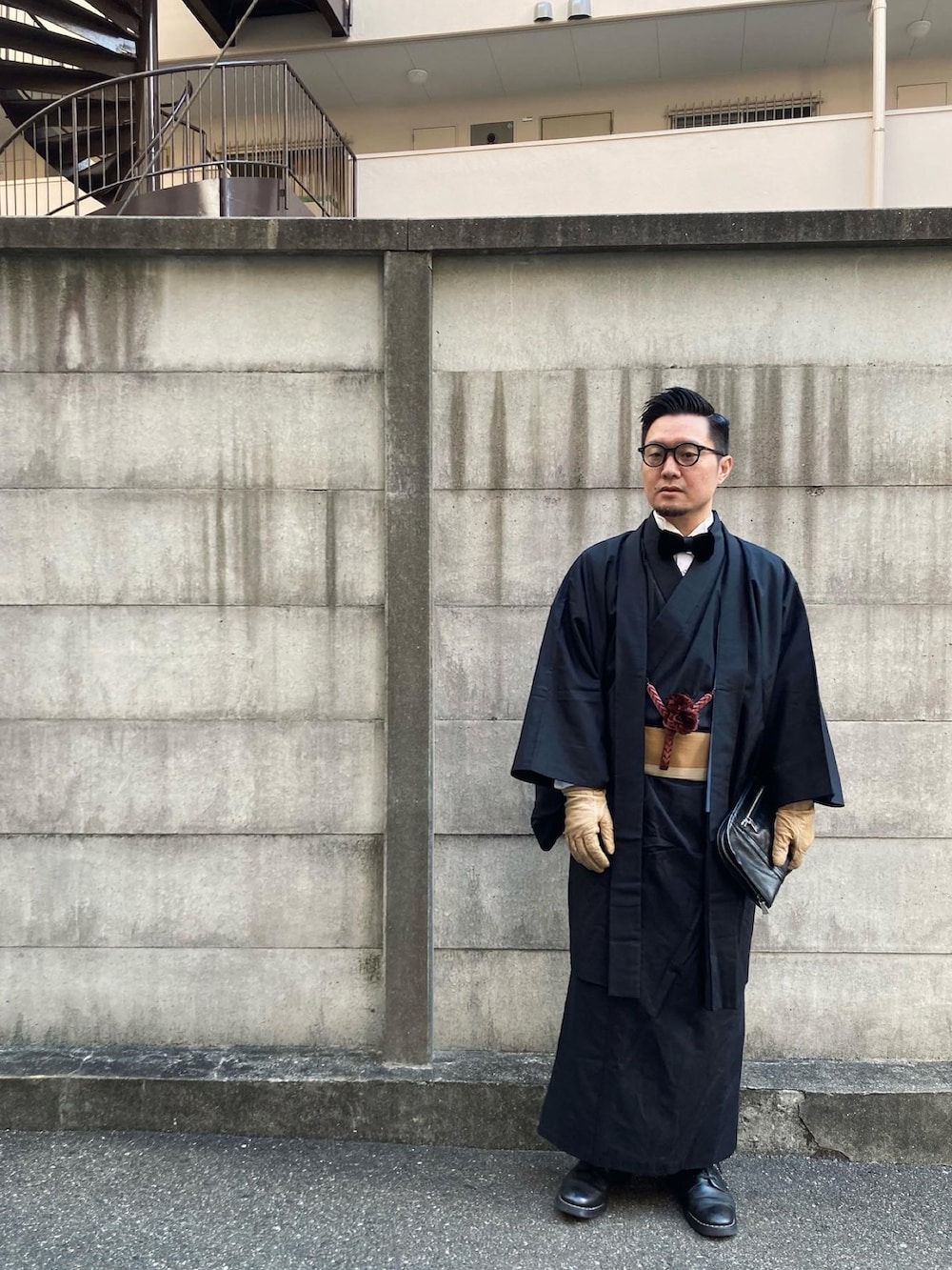 ブラック系のブーツ、ブラック系の蝶ネクタイ、ブラック系のクラッチバッグを着用したメンズの冬コーディネートの2枚目の写真