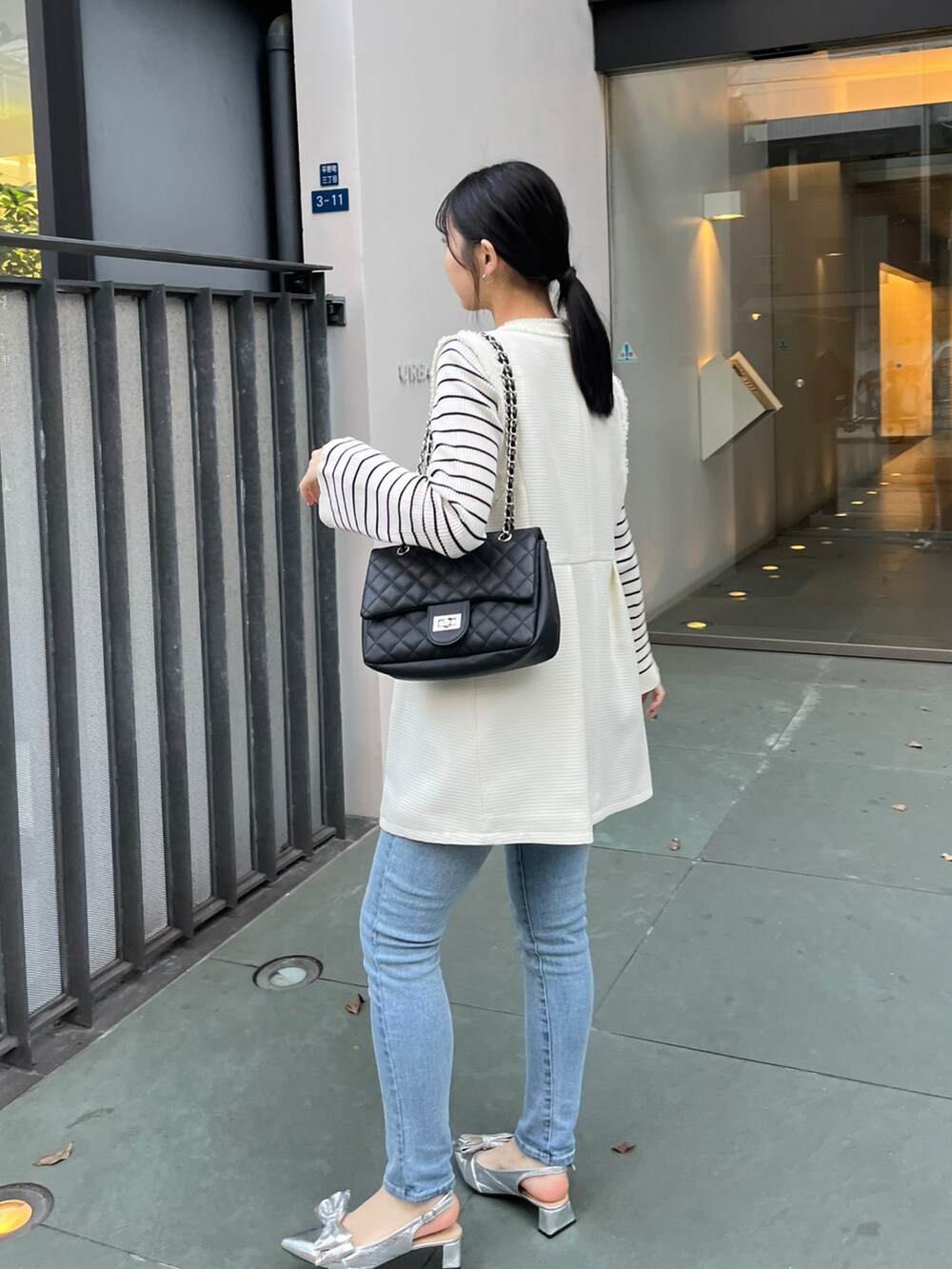 ブルー系のデニムパンツ、ホワイト系のニット/セーター、ホワイト系のベストを着用したレディースの冬コーディネートの4枚目の写真
