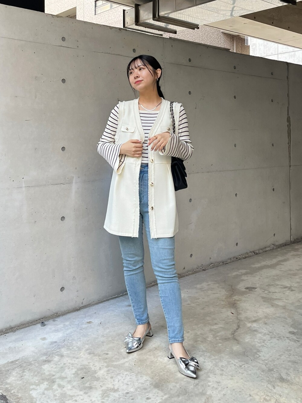 ブルー系のデニムパンツ、ホワイト系のニット/セーター、ホワイト系のベストを着用したレディースの冬コーディネートの2枚目の写真