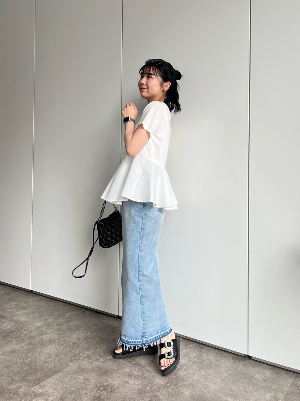 ホワイト系のTシャツ/カットソー、ブルー系のデニムスカート、ブラック系のサンダルを着用したレディースの春コーディネートの3枚目の写真