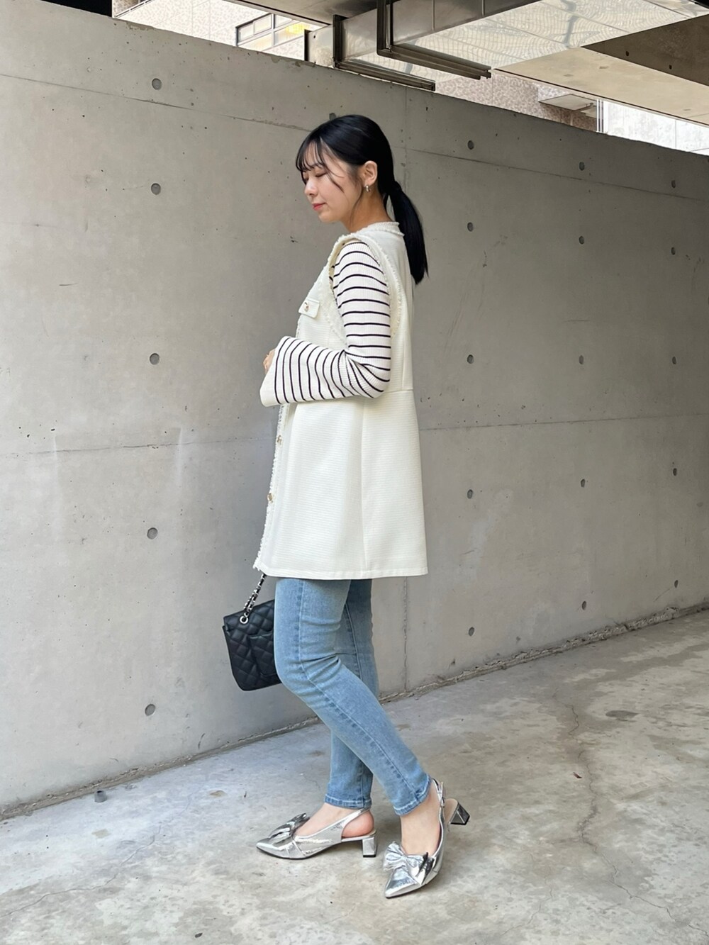 ブルー系のデニムパンツ、ホワイト系のニット/セーター、ホワイト系のベストを着用したレディースの冬コーディネートの3枚目の写真