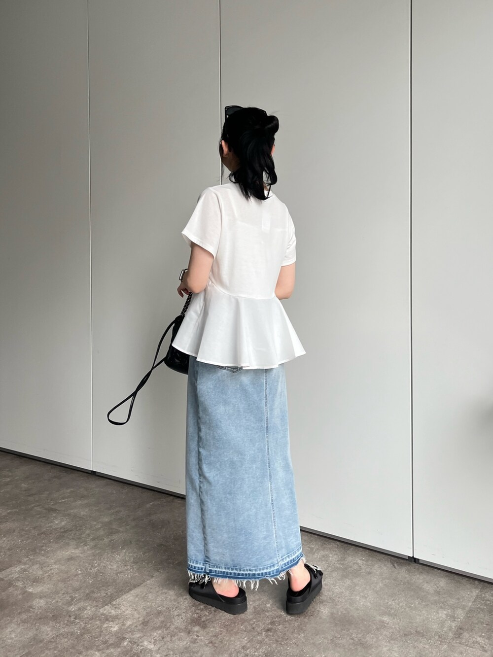 ホワイト系のTシャツ/カットソー、ブルー系のデニムスカート、ブラック系のサンダルを着用したレディースの春コーディネートの4枚目の写真