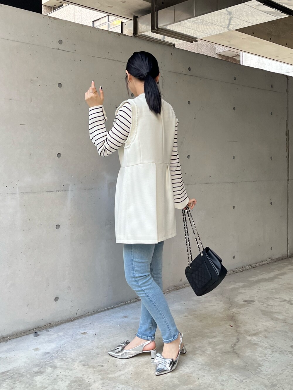 ブルー系のデニムパンツ、ホワイト系のニット/セーター、ホワイト系のベストを着用したレディースの冬コーディネートの5枚目の写真