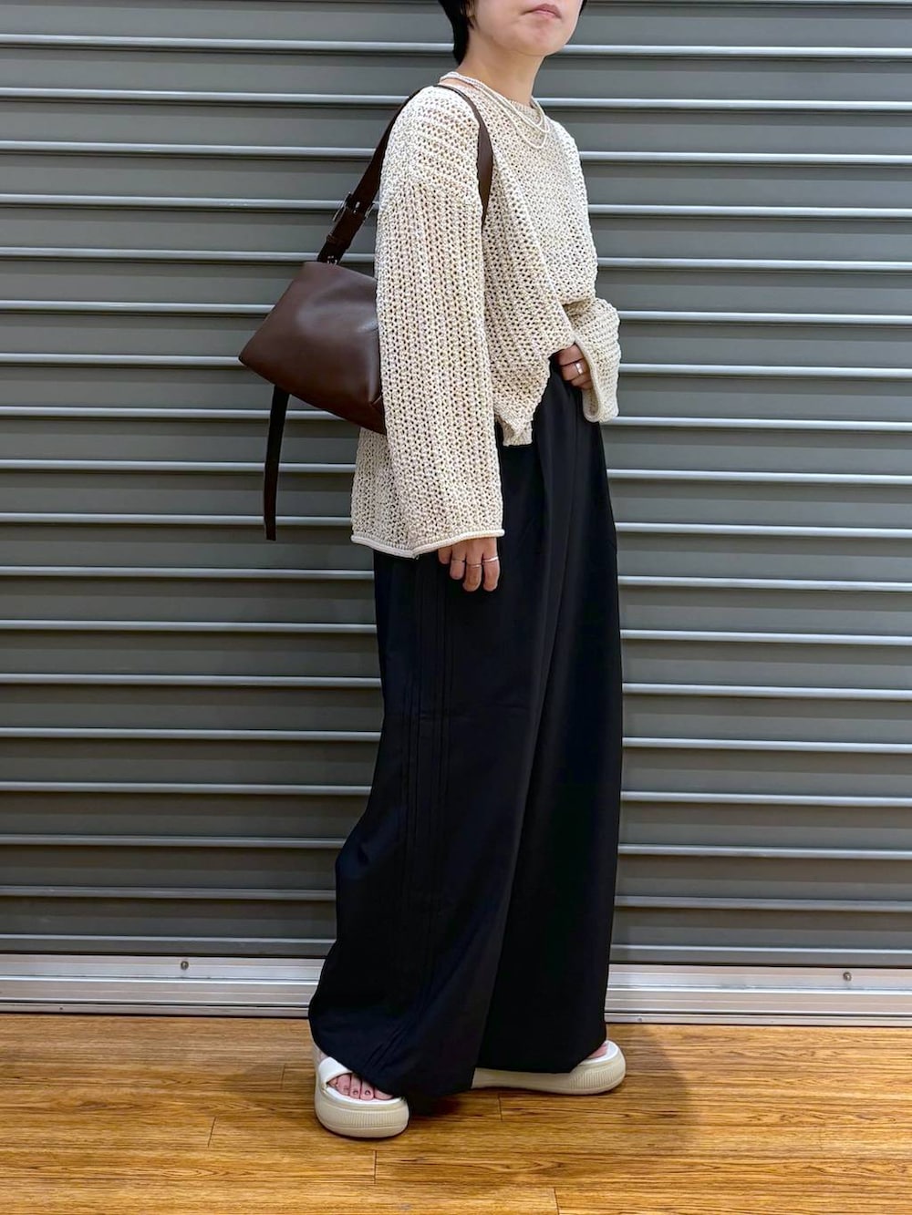 ブラック系のショルダーバッグ、ホワイト系のニット/セーター、ブラック系のその他パンツを着用したレディースの夏コーディネートの2枚目の写真