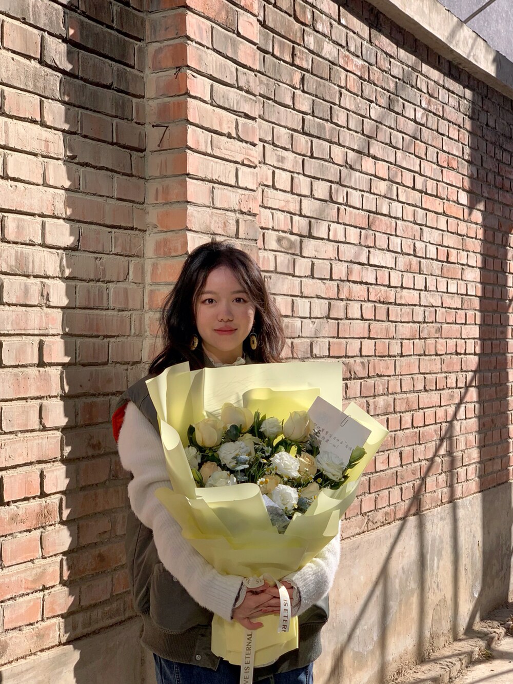 グリーン系のMA-1、オレンジ系のイヤリングを着用したレディースの春コーディネートの2枚目の写真