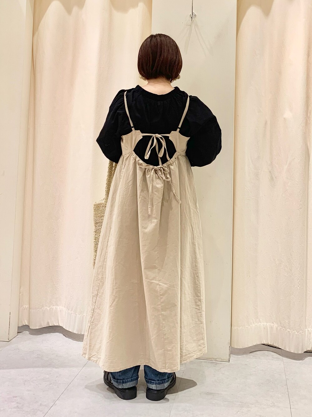 ホワイト系のハンドバッグ、ブルー系のデニムパンツ、ブラック系のサンダルを着用したレディースの春コーディネートの3枚目の写真