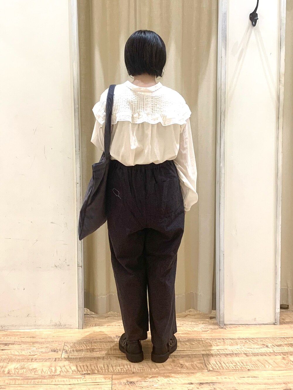 グレー系のハンドバッグ、ブラック系のパンツ、ブラック系のドレスシューズを着用したレディースの秋コーディネートの2枚目の写真