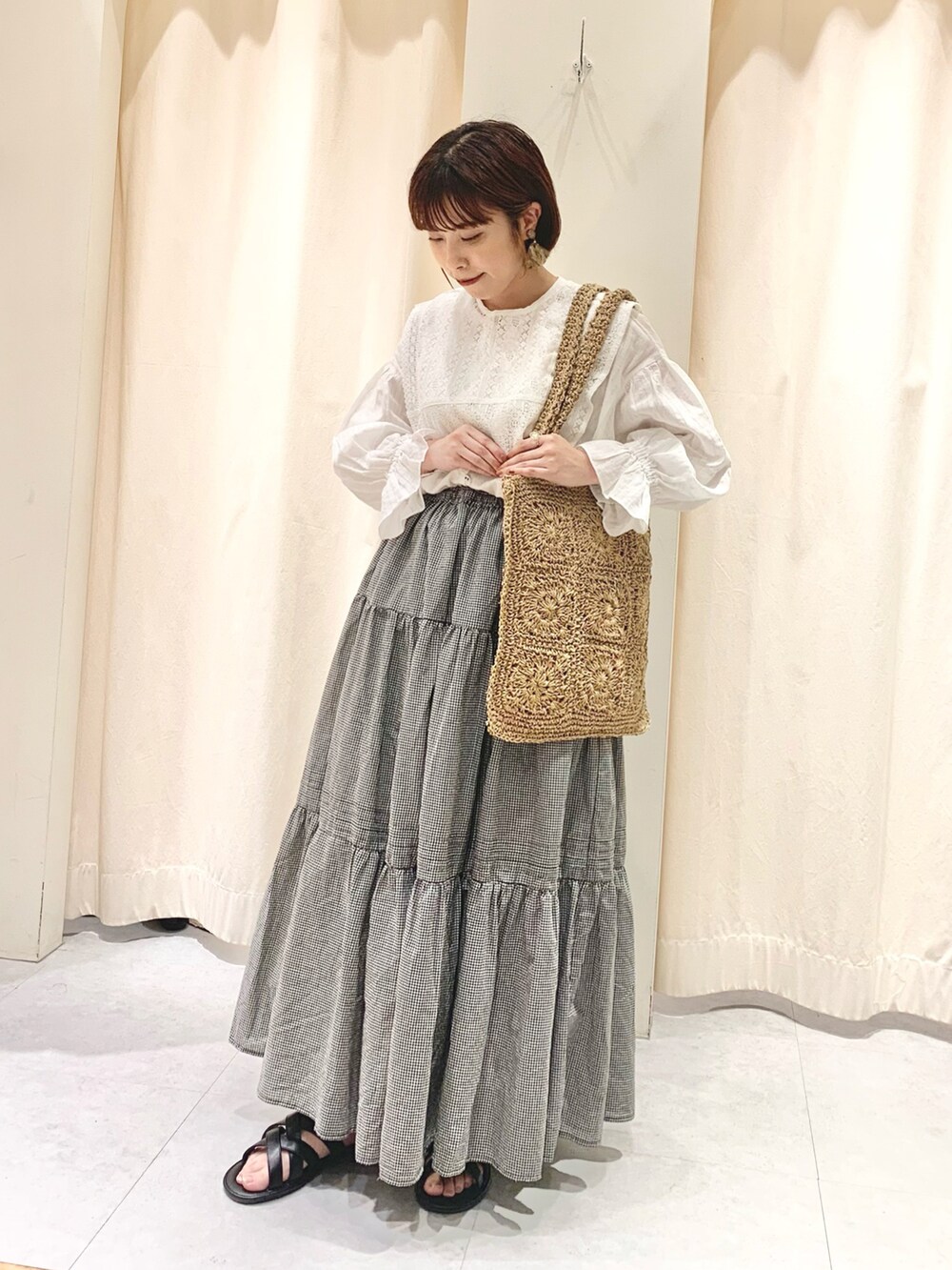 ベージュ系のハンドバッグ、ホワイト系のシャツ/ブラウス、ブラック系のサンダルを着用したレディースの春コーディネートの2枚目の写真