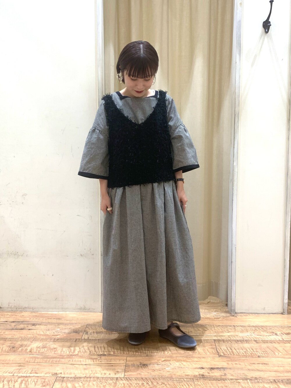 ブラック系のベスト、グレー系のドレスシューズ、ベージュ系のワンピースを着用したレディースの夏コーディネートの2枚目の写真