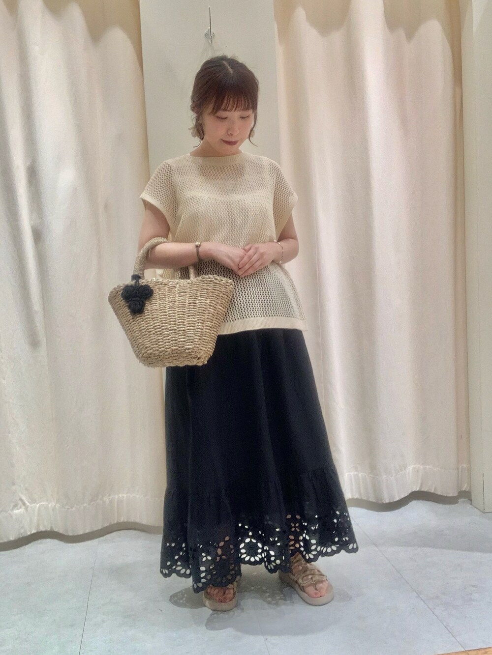 ホワイト系のベスト、ベージュ系のバッグ、ホワイト系のスカートを着用したレディースの夏コーディネートの2枚目の写真