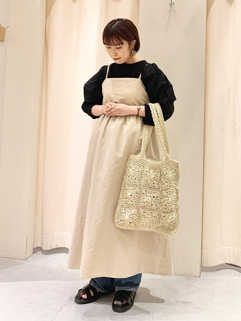 ホワイト系のハンドバッグ、ブルー系のデニムパンツ、ブラック系のサンダルを着用したレディースの春コーディネートの2枚目の写真