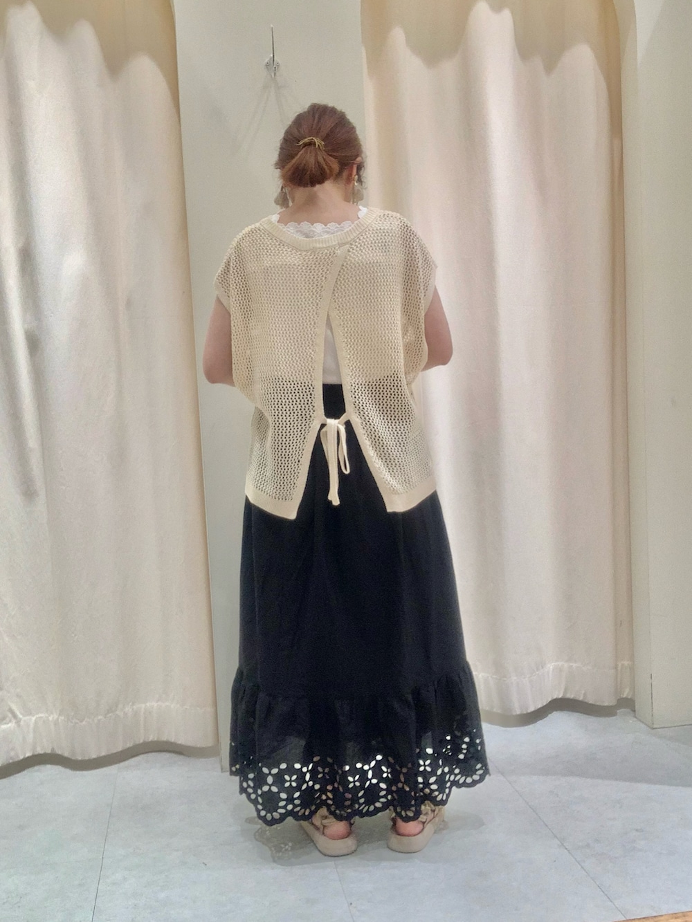 ホワイト系のベスト、ベージュ系のバッグ、ホワイト系のスカートを着用したレディースの夏コーディネートの3枚目の写真