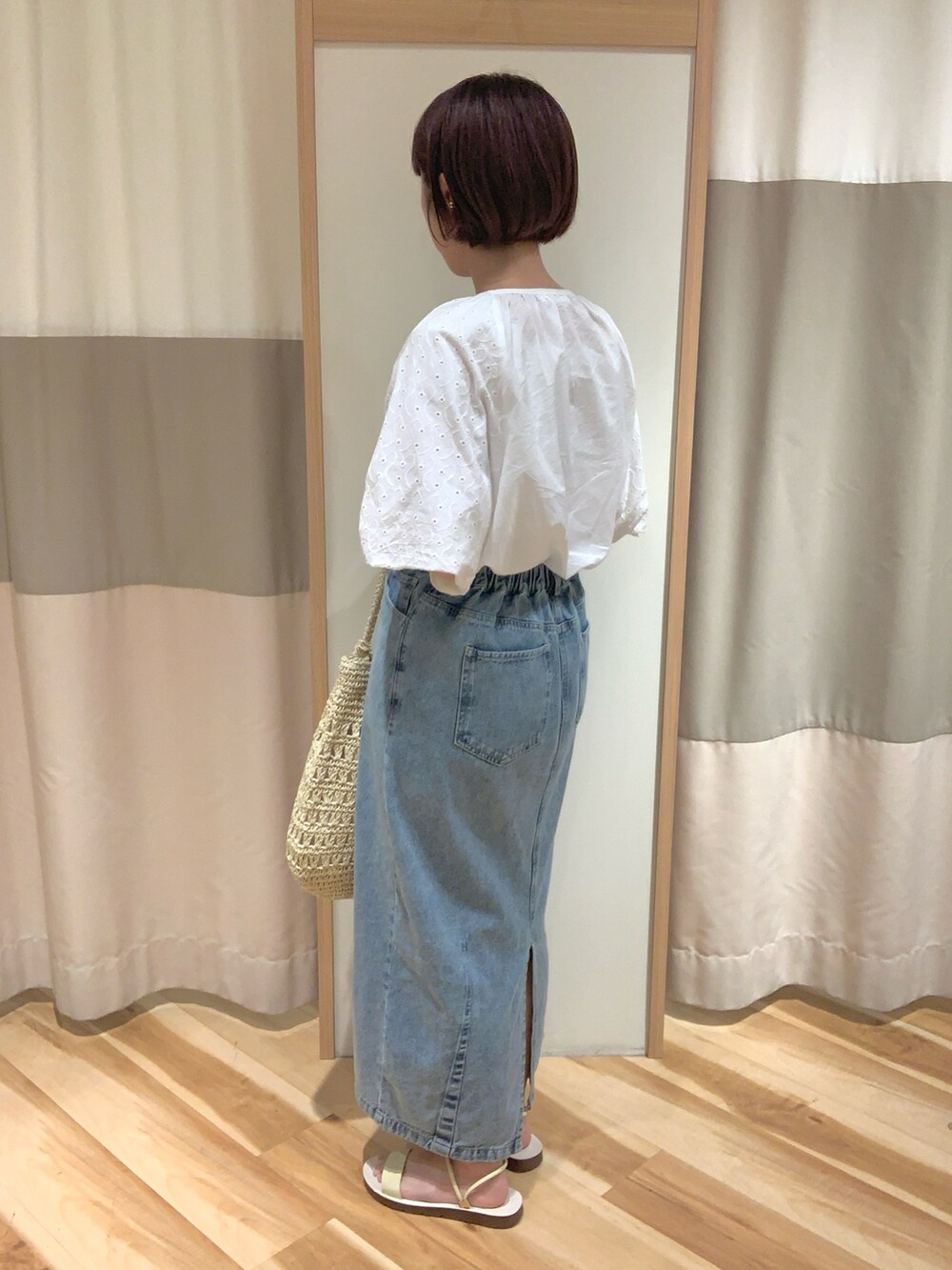 ベージュ系のハンドバッグ、ホワイト系のシャツ/ブラウス、ブルー系のスカートを着用したレディースの夏コーディネートの2枚目の写真