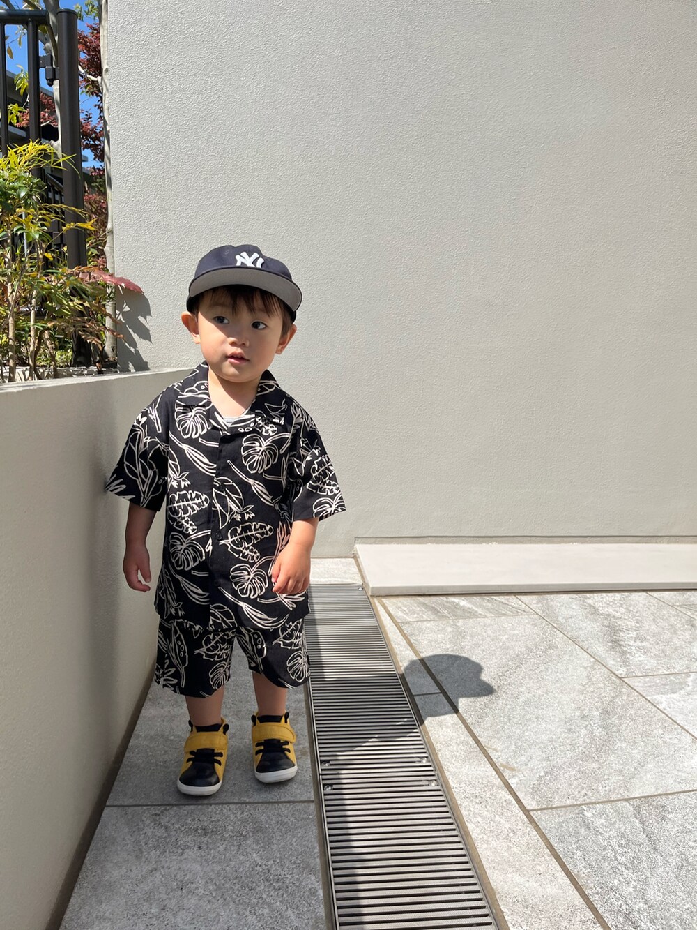 イエロー系のスニーカー、ブラック系のアンサンブル、ブルー系のキャップを着用したキッズの秋コーディネートの2枚目の写真