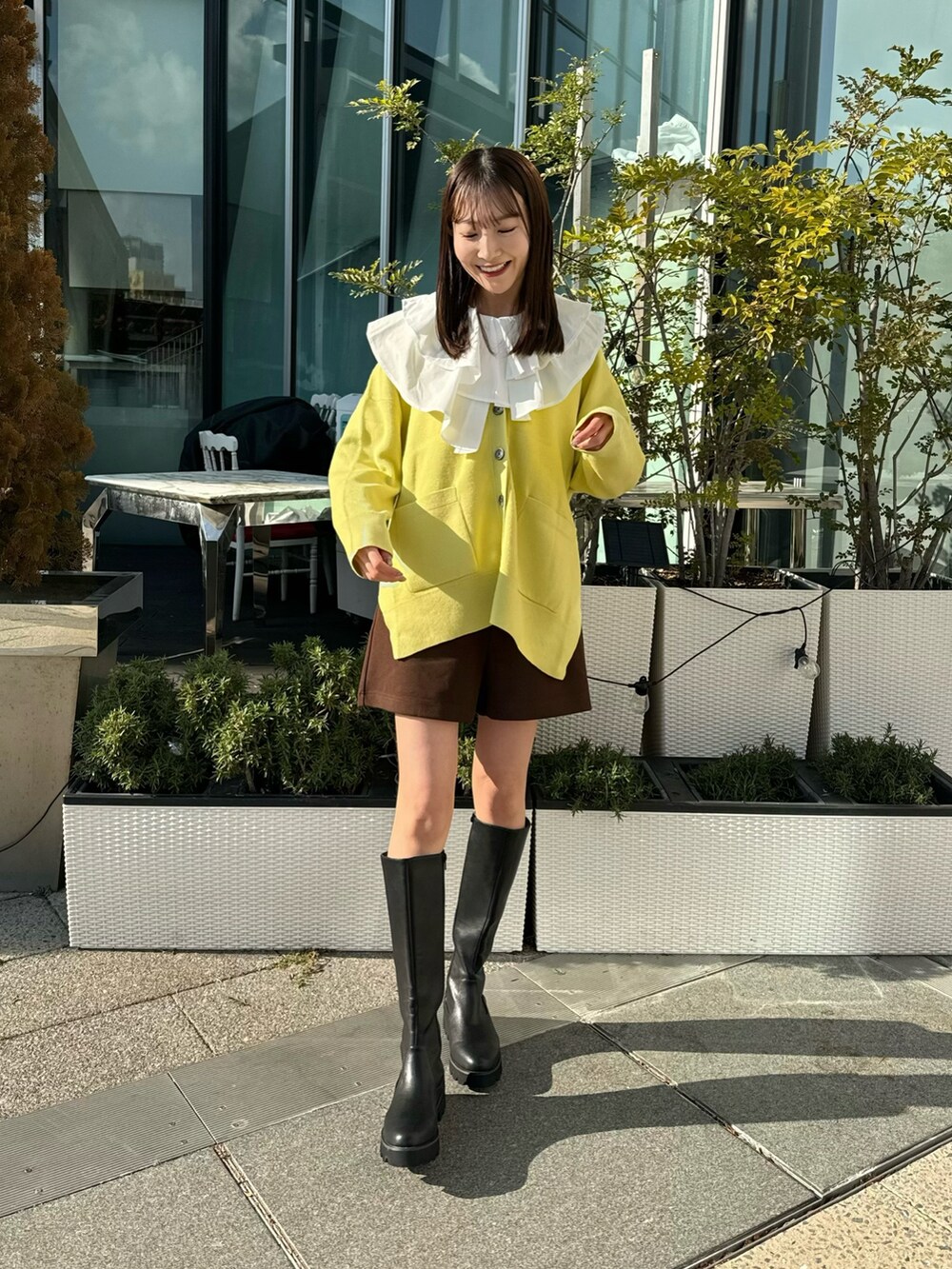 イエロー系のカーディガン/ボレロ、ホワイト系のチュニック、ブラウン系のその他パンツを着用したレディースの冬コーディネートの3枚目の写真