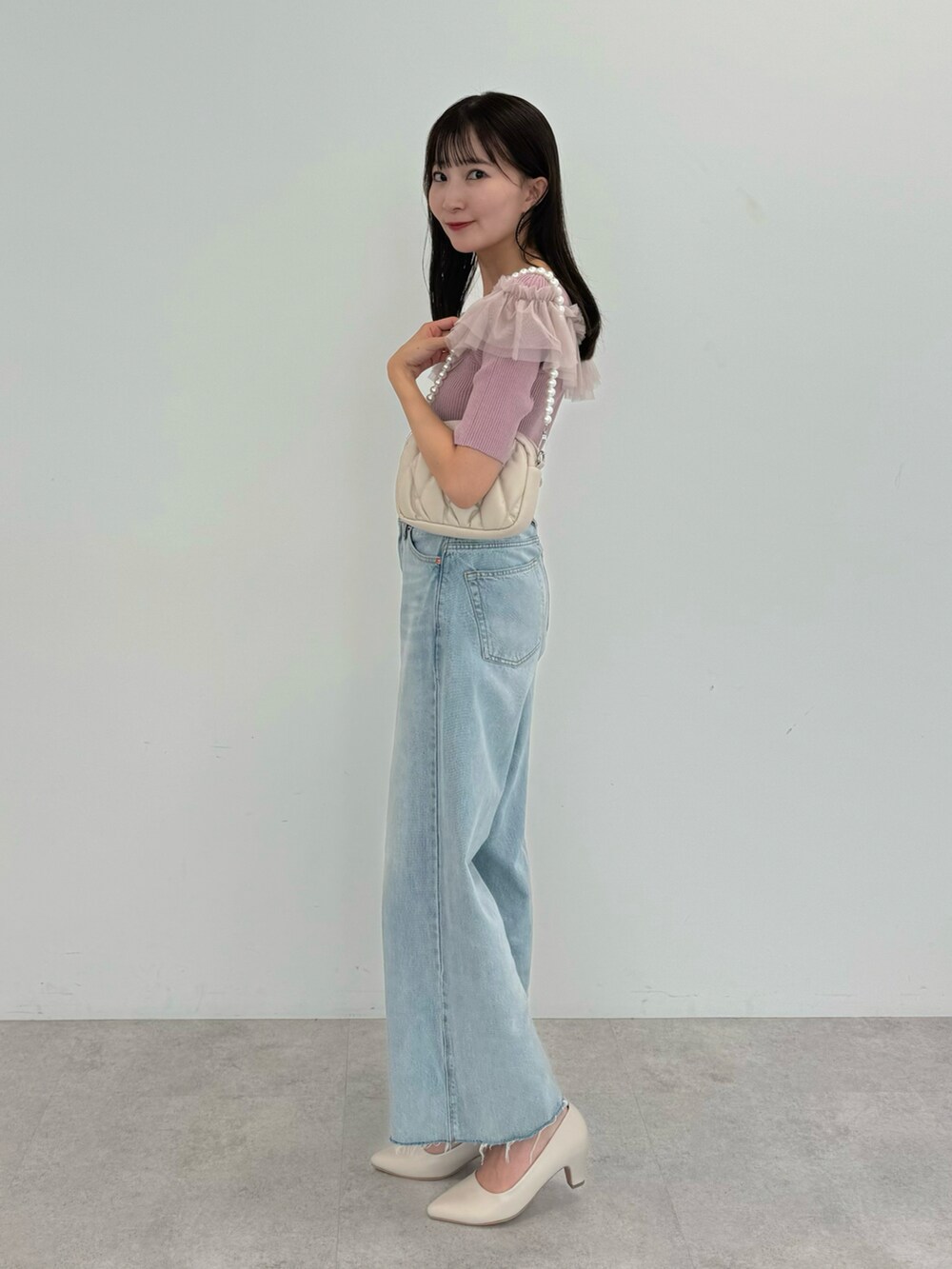 ブルー系のデニムパンツ、ピンク系のニット/セーター、ベージュ系のパンプスを着用したレディースの夏コーディネートの2枚目の写真