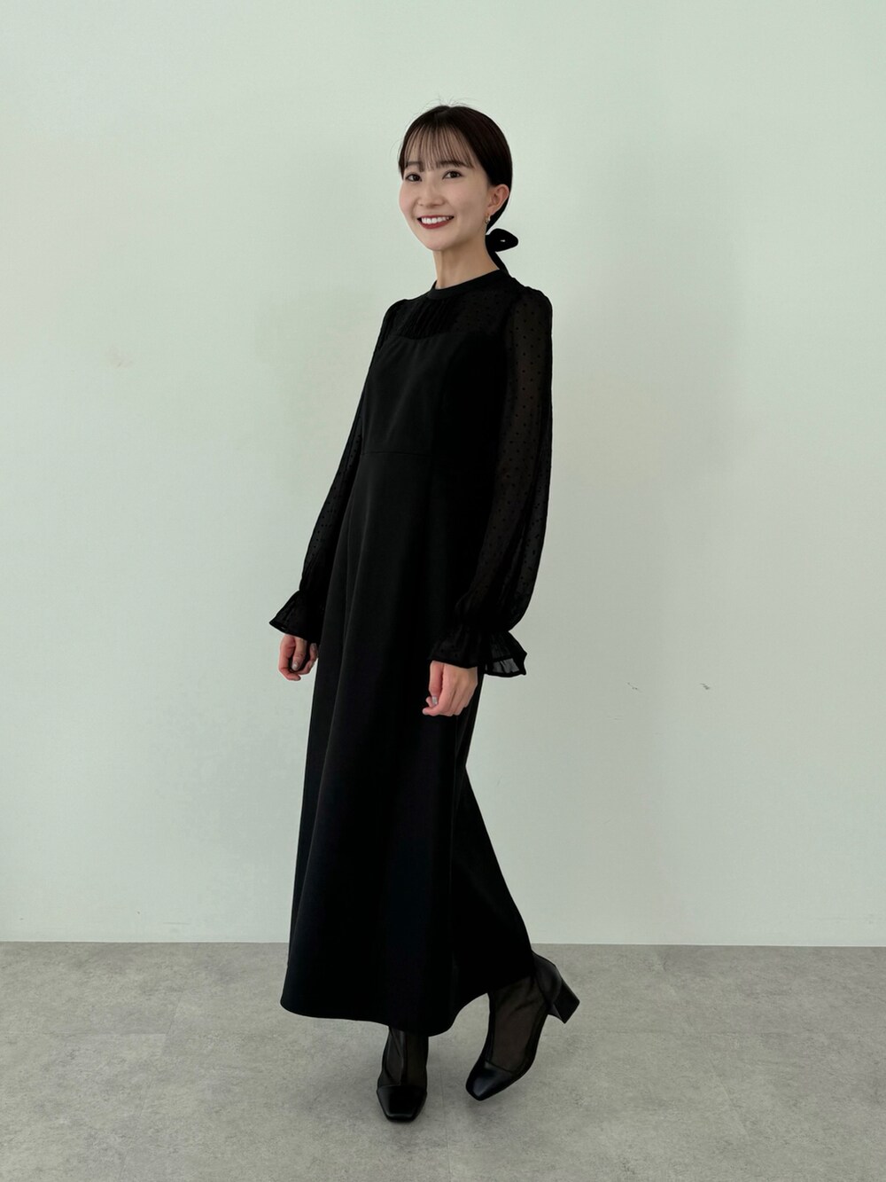 ブラック系のドレス、ブラック系のブーツを着用したレディースの春コーディネートの2枚目の写真