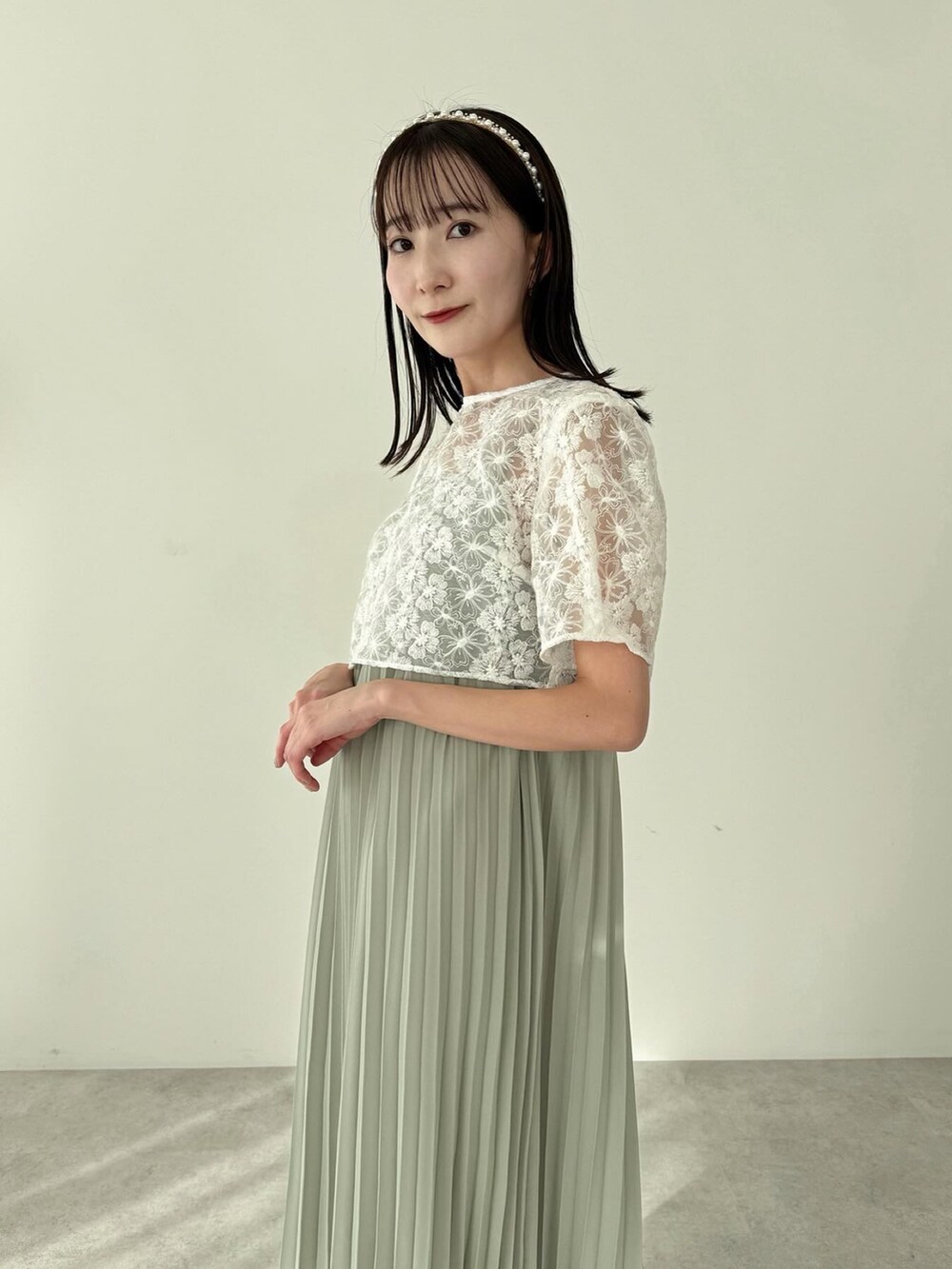 グリーン系のワンピース、ホワイト系のショルダーバッグを着用したレディースの冬コーディネートの5枚目の写真