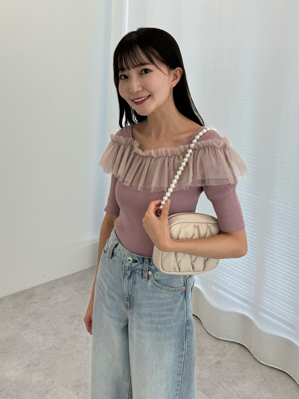 ブルー系のデニムパンツ、ピンク系のニット/セーター、ベージュ系のパンプスを着用したレディースの夏コーディネートの3枚目の写真