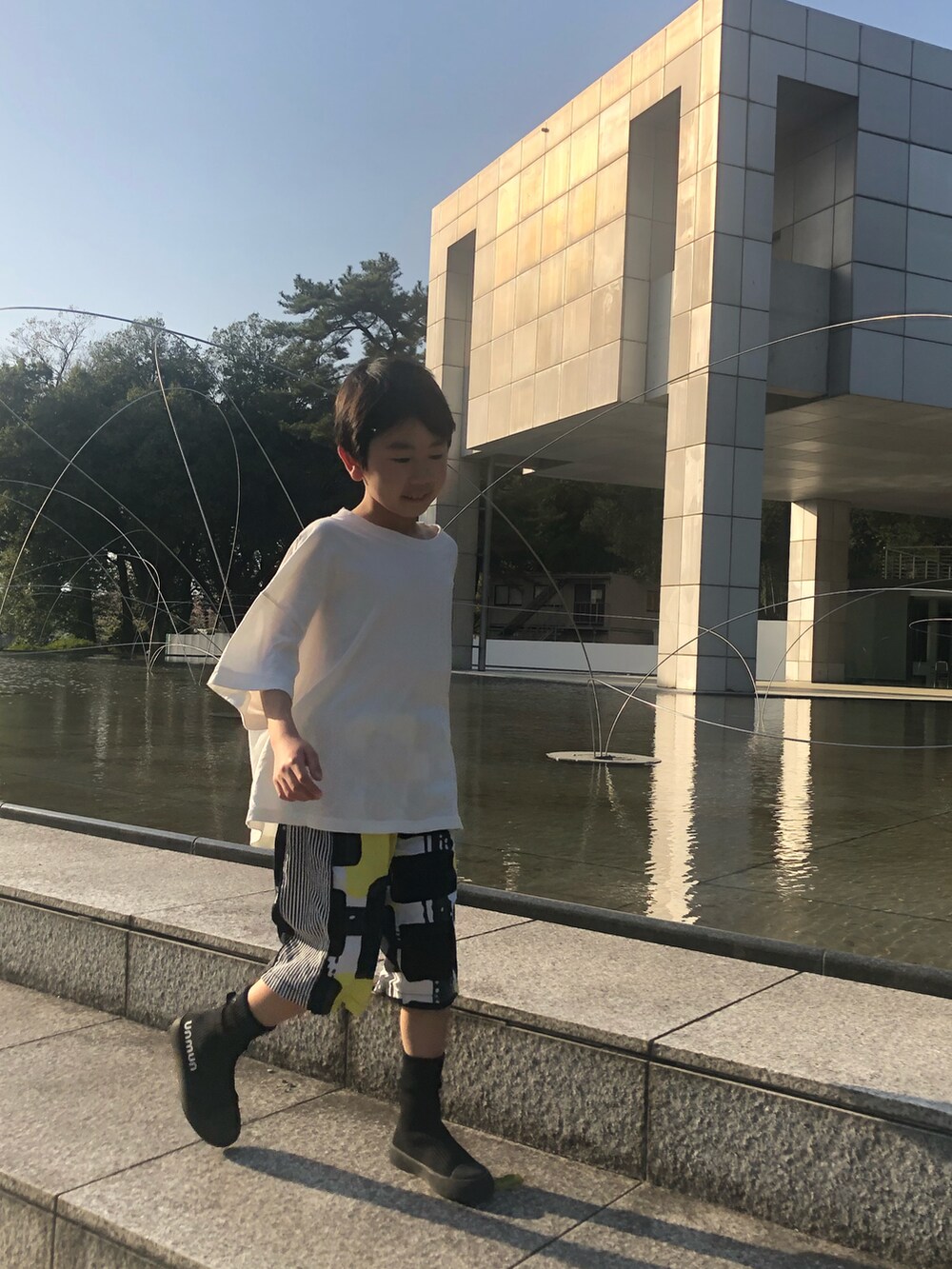 ホワイト系のTシャツ/カットソー、イエロー系のパンツ、ブラック系のシューズを着用したキッズの春コーディネートの4枚目の写真