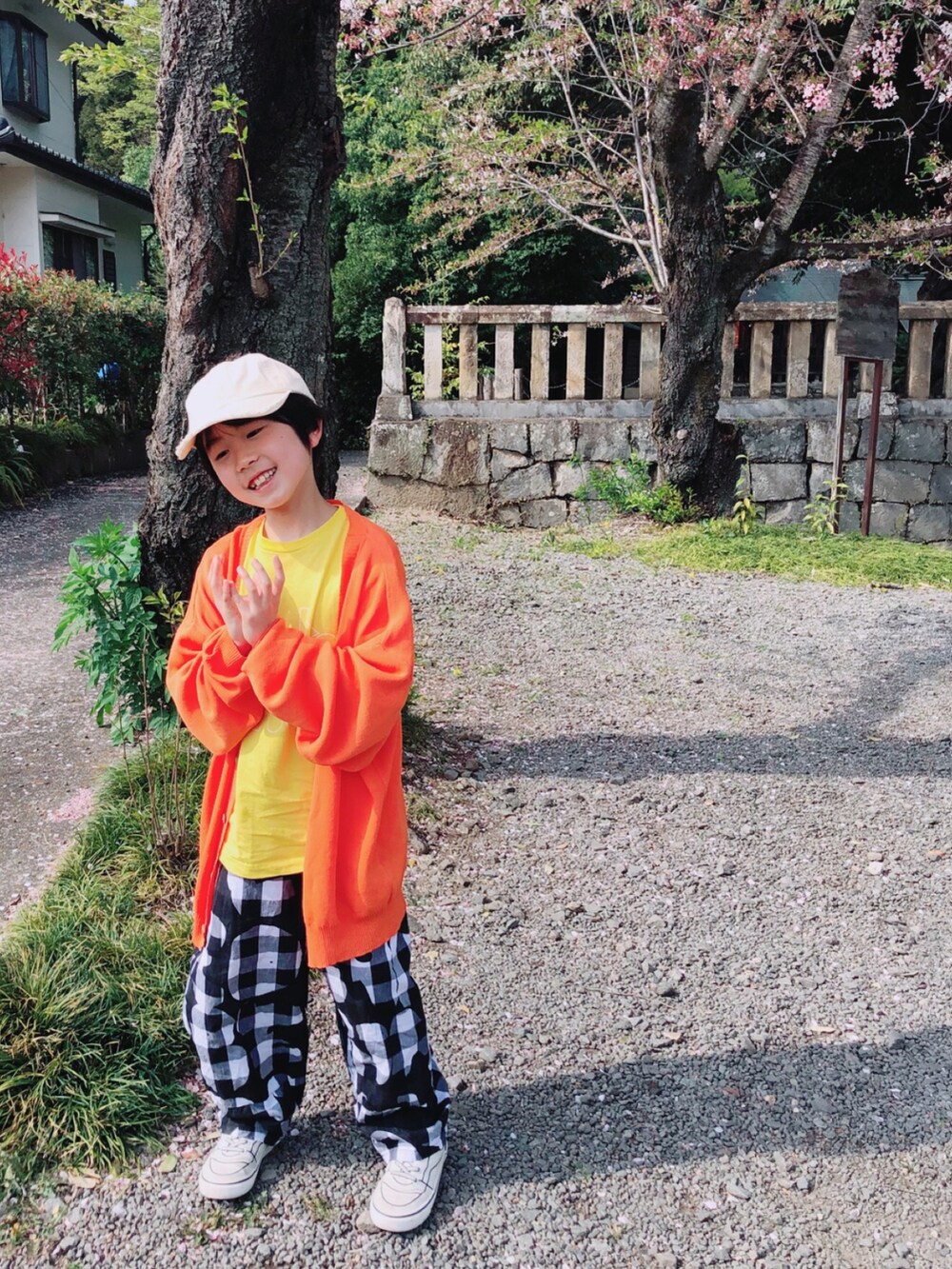 オレンジ系のカーディガン/ボレロ、ブラック系のパンツ、イエロー系のTシャツ/カットソーを着用したキッズの春コーディネートの2枚目の写真