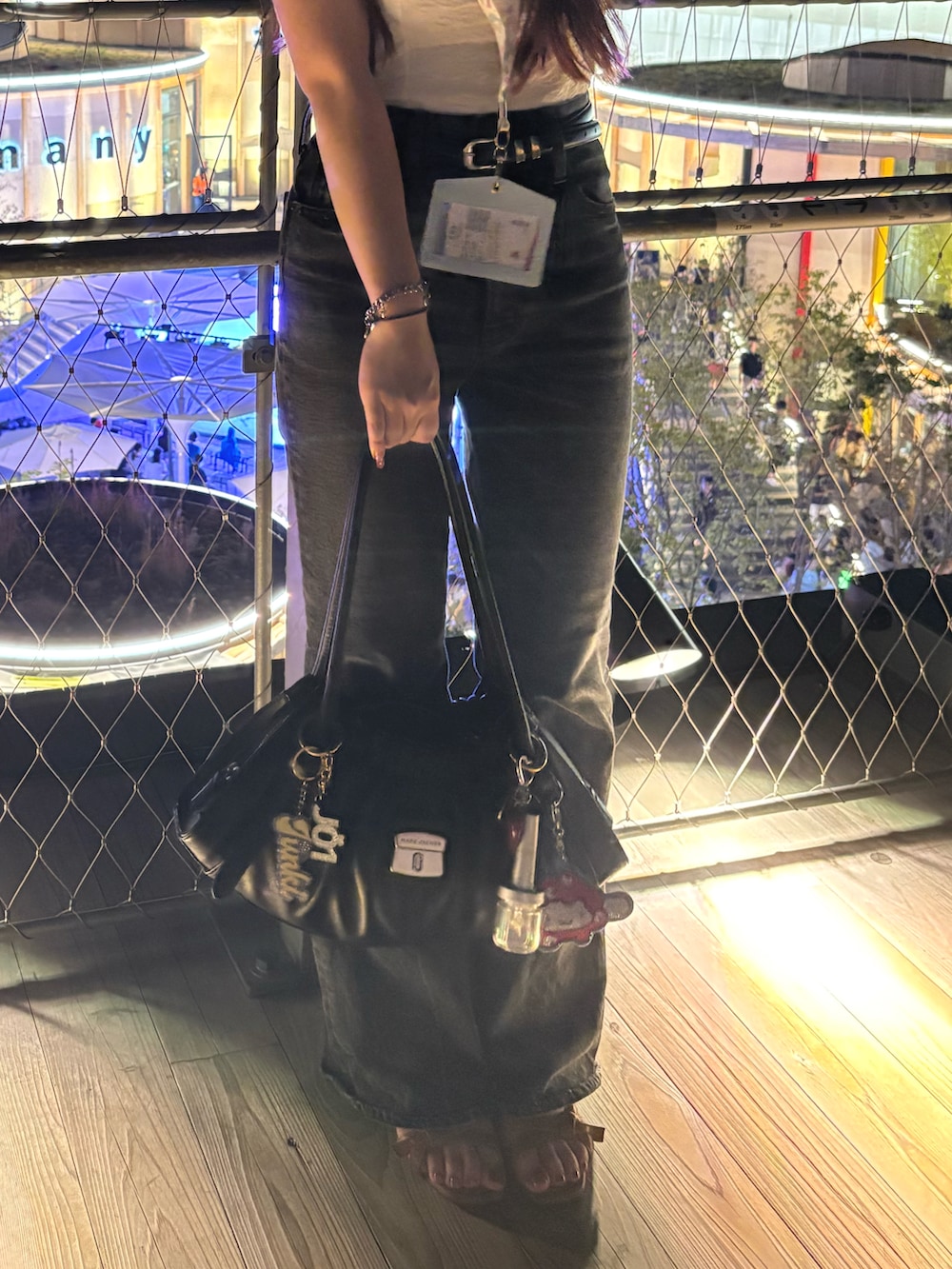 ブラック系のデニムパンツ、ブラック系のショルダーバッグ、ブラウン系のサンダルを着用したレディースの秋コーディネートの2枚目の写真