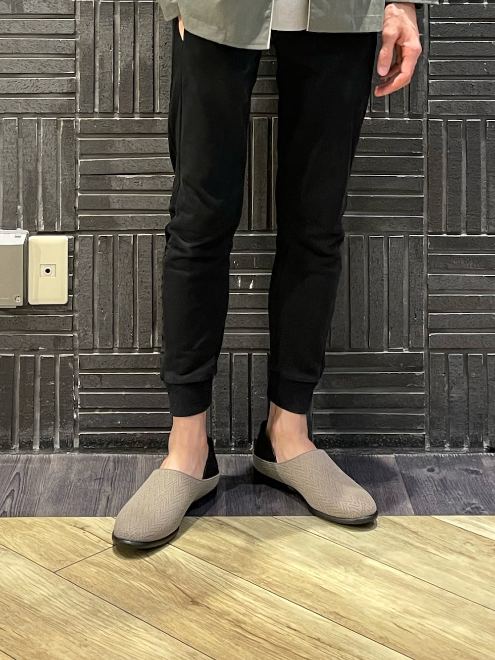 ブラック系のスウェットパンツ、ベージュ系のニット/セーター、グリーン系のシャツ/ブラウスを着用したメンズの春コーディネートの2枚目の写真