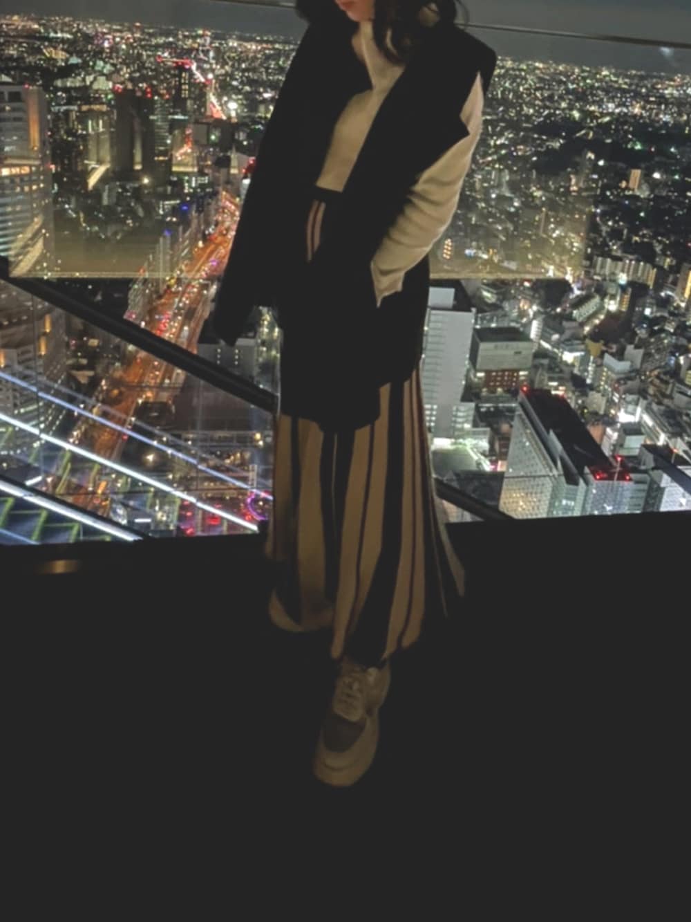 ブラック系のベスト、ホワイト系のトップス、ブラウン系のスカートを着用したレディースの秋コーディネートの3枚目の写真