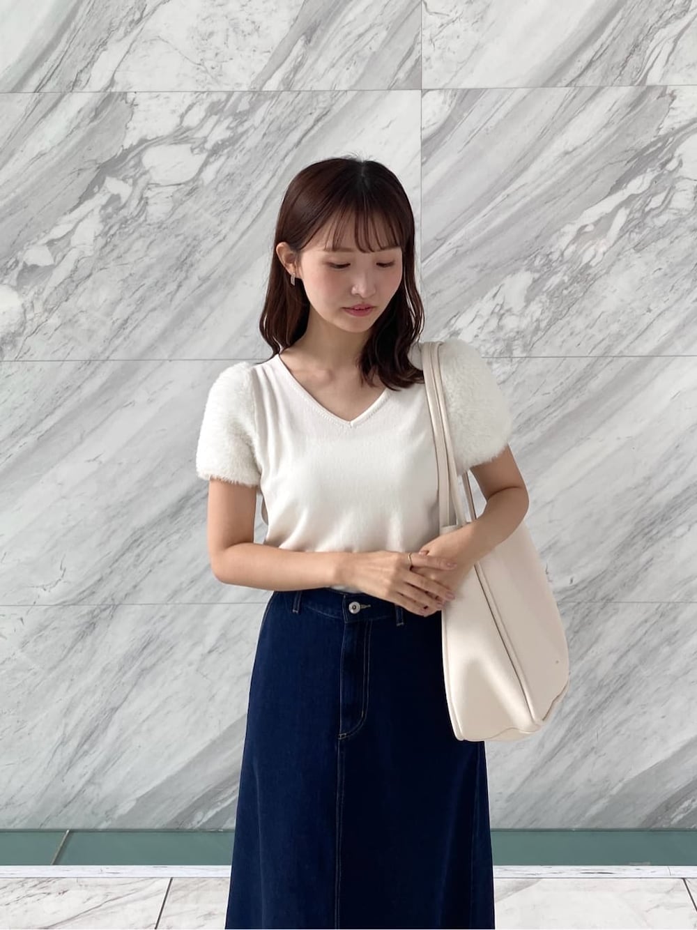 ホワイト系のニット/セーター、ブルー系のデニムスカート、ホワイト系のトートバッグを着用したレディースの夏コーディネートの8枚目の写真