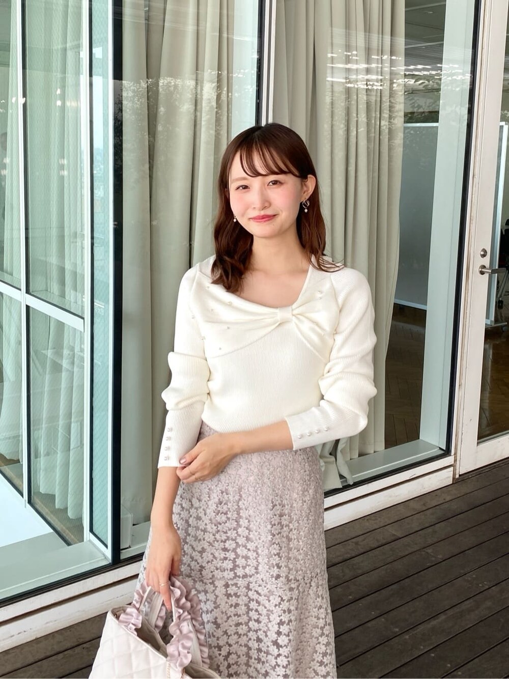ホワイト系のニット/セーター、ベージュ系のスカート、ホワイト系のトートバッグを着用したレディースの秋コーディネートの7枚目の写真