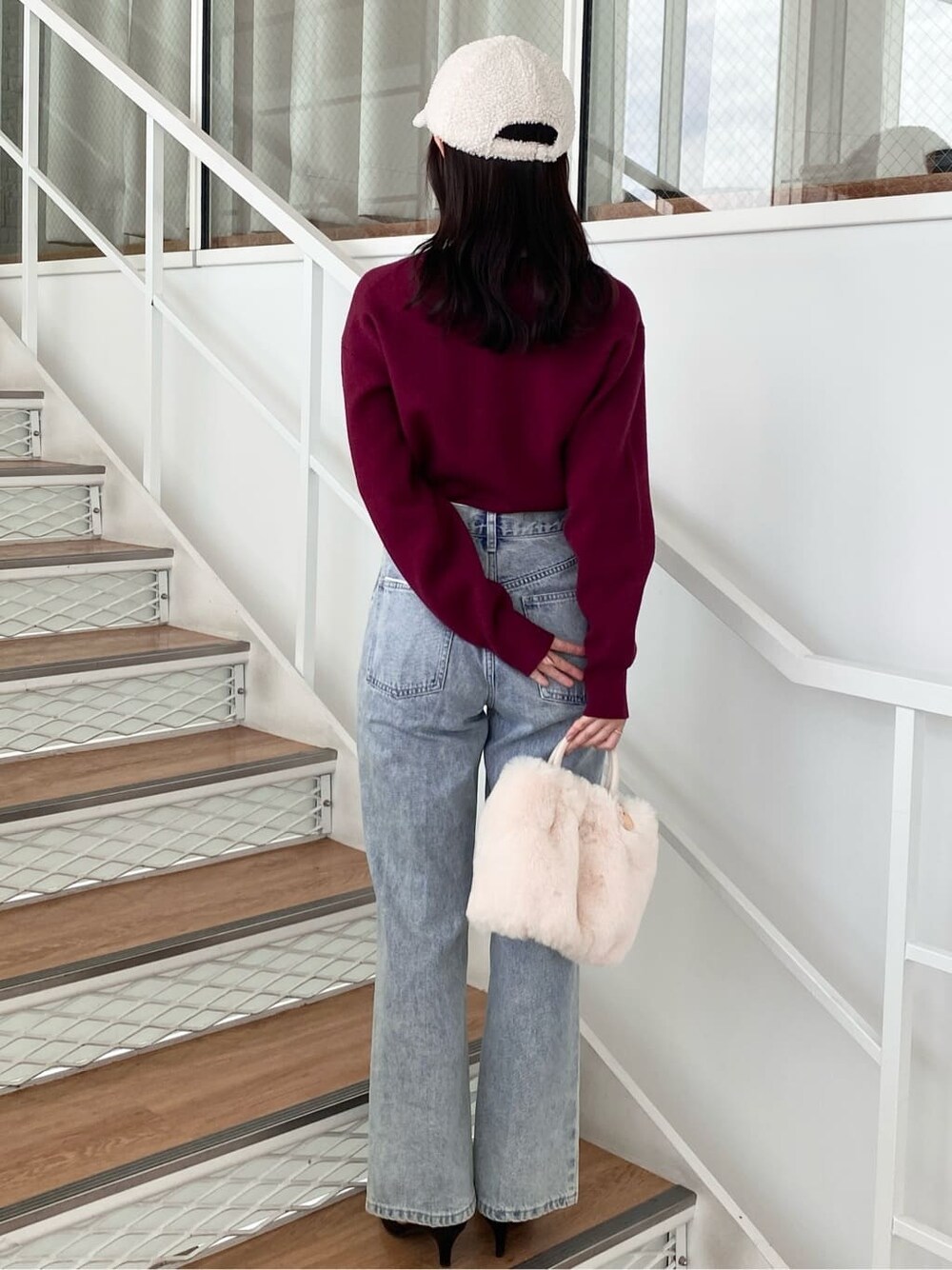 レッド系のニット/セーター、ブラック系のデニムパンツ、ホワイト系のショルダーバッグを着用したレディースの冬コーディネートの5枚目の写真