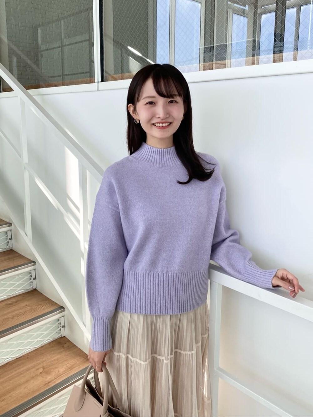 パープル系のニット/セーター、ベージュ系のスカート、ベージュ系のボストンバッグを着用したレディースの冬コーディネートの6枚目の写真