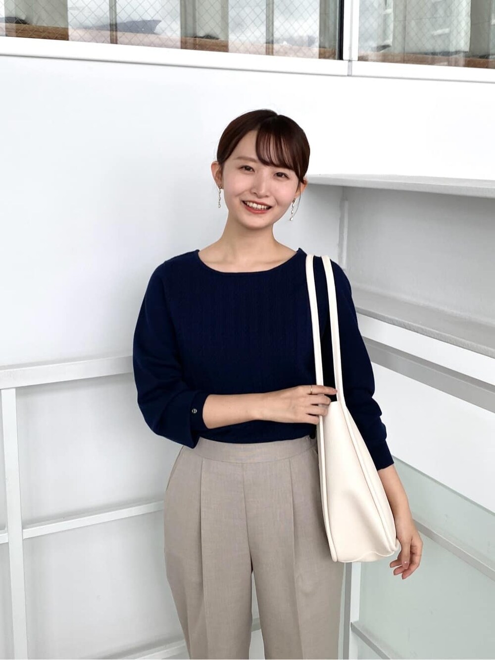 ブルー系のニット/セーター、ベージュ系のその他パンツ、ホワイト系のトートバッグを着用したレディースの秋コーディネートの6枚目の写真