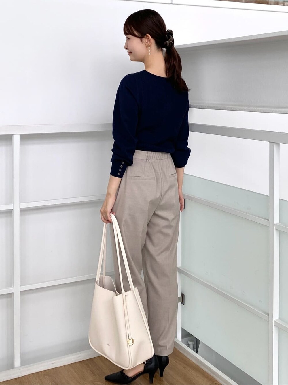 ブルー系のニット/セーター、ベージュ系のその他パンツ、ホワイト系のトートバッグを着用したレディースの秋コーディネートの5枚目の写真