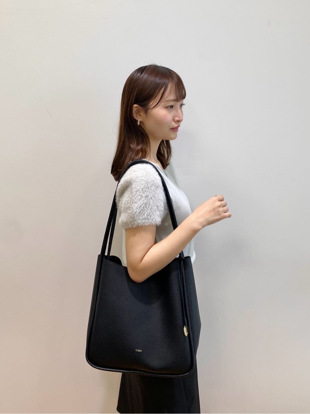 グリーン系のニット/セーター、ブラック系のスカート、ブラック系のトートバッグを着用したレディースの夏コーディネートの7枚目の写真