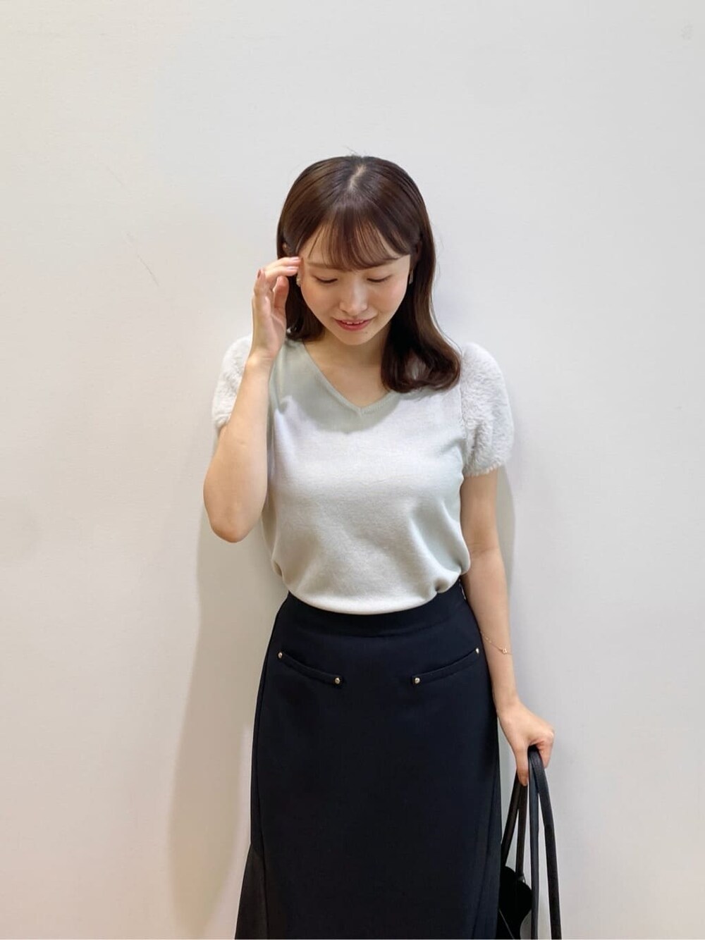 グリーン系のニット/セーター、ブラック系のスカート、ブラック系のトートバッグを着用したレディースの夏コーディネートの6枚目の写真