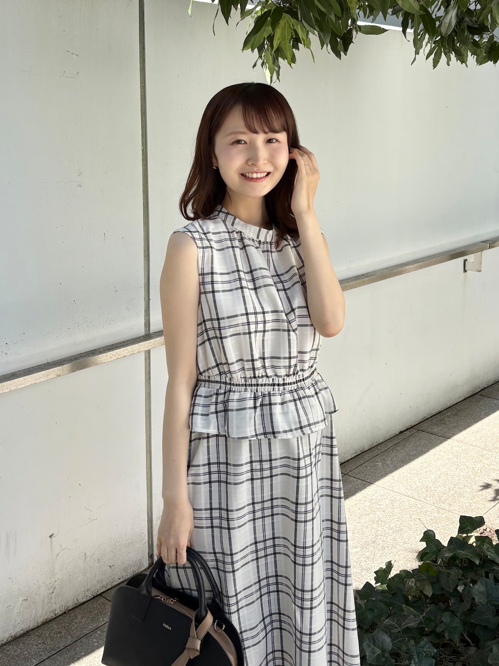 ブラック系のボストンバッグ、ブラック系のパンプス、ゴールド系のピアス(両耳用)を着用したレディースの春コーディネートの7枚目の写真