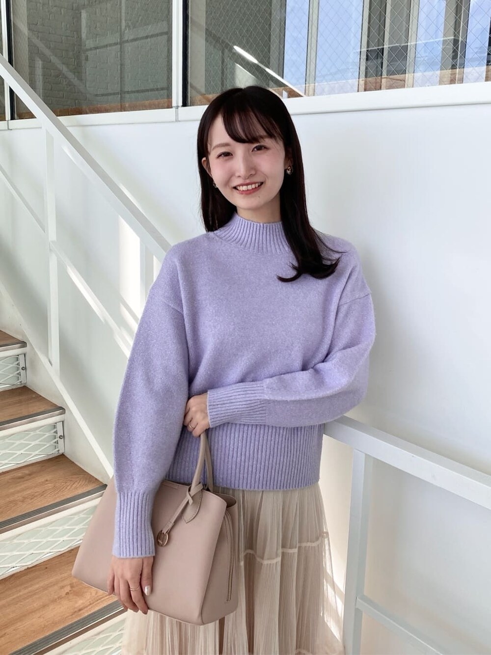パープル系のニット/セーター、ベージュ系のスカート、ベージュ系のボストンバッグを着用したレディースの冬コーディネートの8枚目の写真