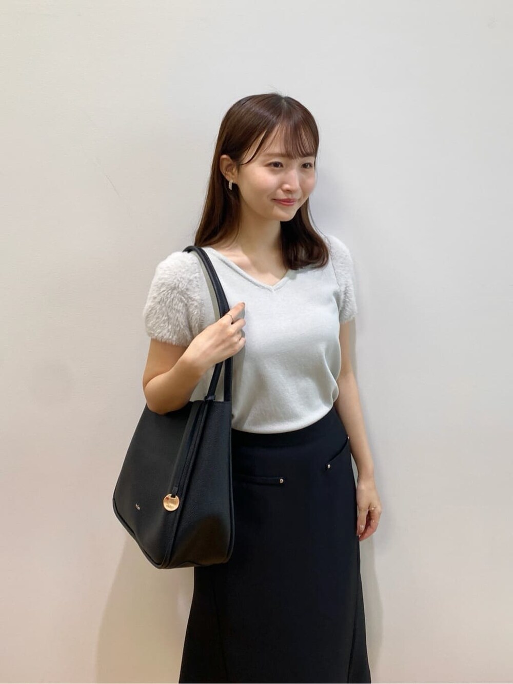 グリーン系のニット/セーター、ブラック系のスカート、ブラック系のトートバッグを着用したレディースの夏コーディネートの8枚目の写真