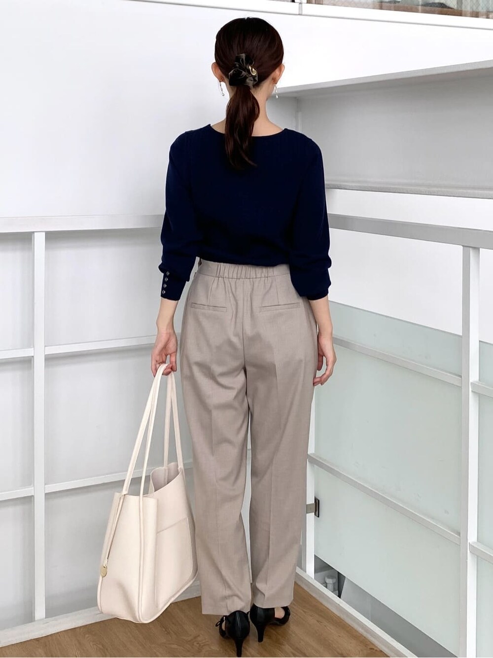 ブルー系のニット/セーター、ベージュ系のその他パンツ、ホワイト系のトートバッグを着用したレディースの秋コーディネートの4枚目の写真