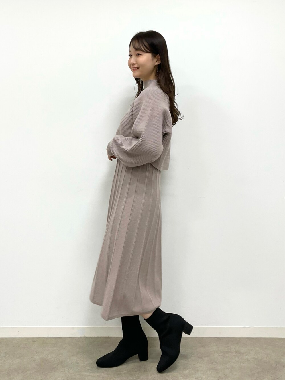 ホワイト系のショルダーバッグ、ブラック系のブーツ、ブラウン系のワンピースを着用したレディースの冬コーディネートの2枚目の写真