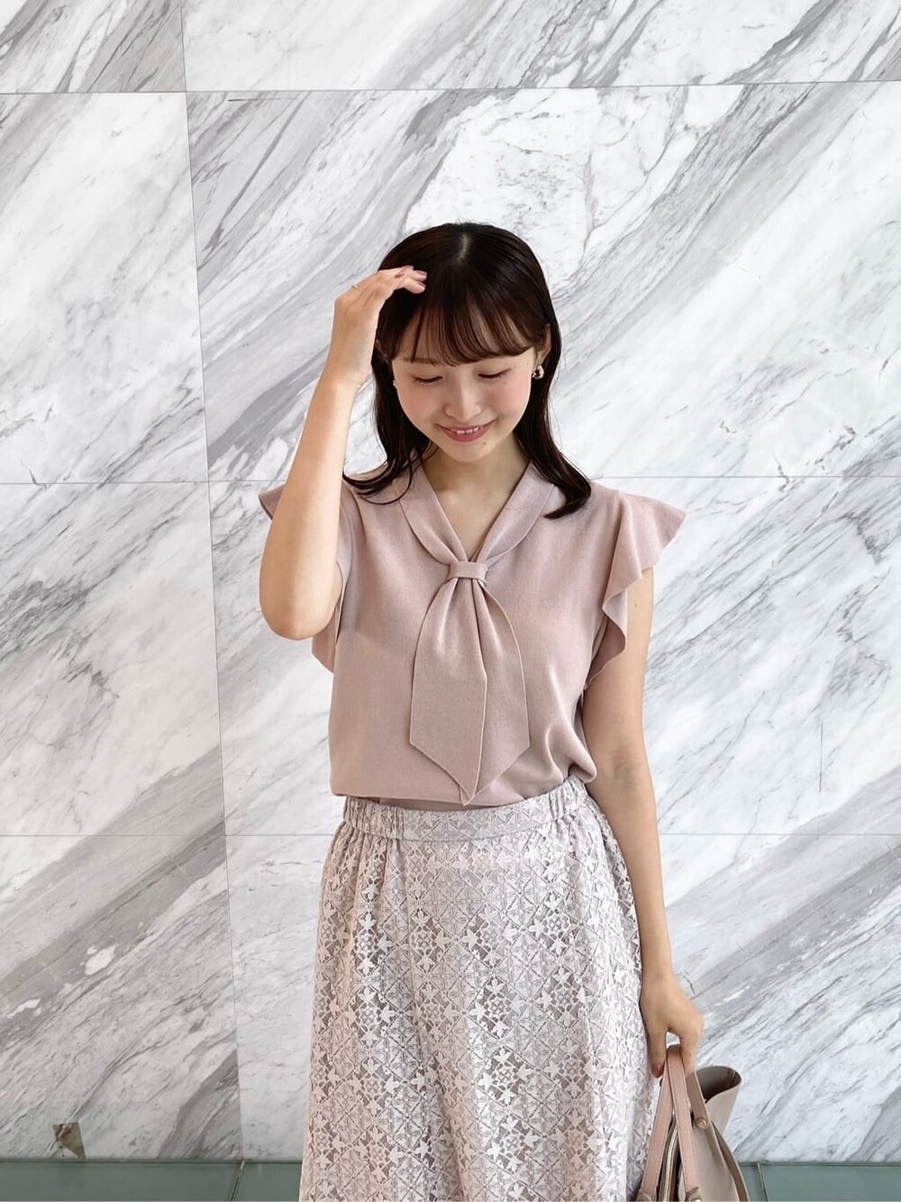 ピンク系のニット/セーター、ベージュ系のスカート、ベージュ系のトートバッグを着用したレディースの夏コーディネートの7枚目の写真