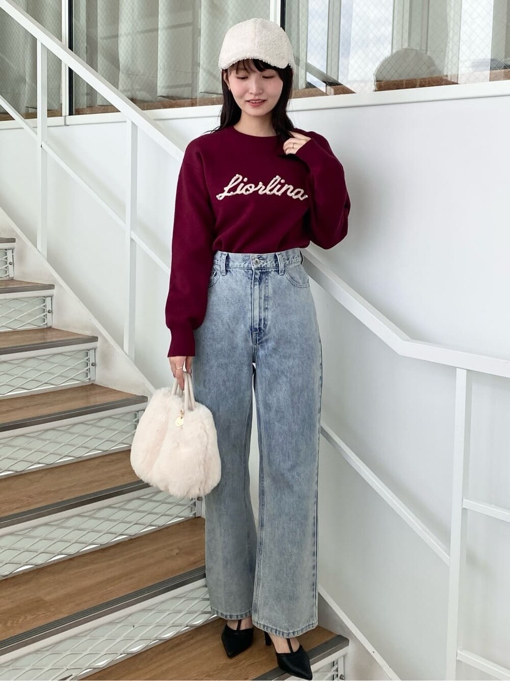 レッド系のニット/セーター、ブラック系のデニムパンツ、ホワイト系のショルダーバッグを着用したレディースの冬コーディネートの2枚目の写真